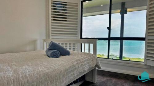 a bedroom with a bed with a blue pillow on it at Peace In Paradise near Nelson Bay- waterviews, spa, adventures in Lemon Tree Passage