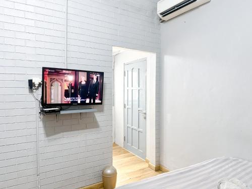 a tv on a white wall in a bedroom at Otu Hostel By Ostic in Yogyakarta