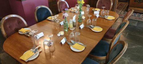 a wooden table with plates and glasses on it at Great Trethew Hotel - Self Catering Lodges - Bar & Restaurant in Liskeard