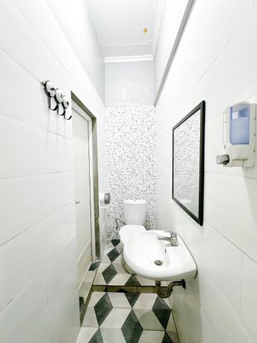 a white bathroom with a sink and a mirror at Otu Hostel By Ostic in Yogyakarta