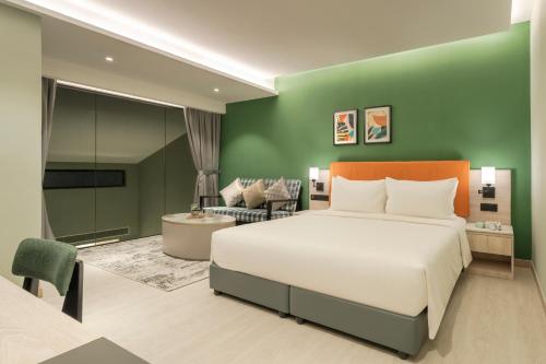 乔治市Citadines Connect Georgetown Penang的卧室配有白色的床和绿色的墙壁