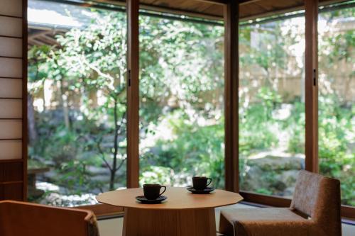two coffee cups on a table in front of a window at 東山露地 Kazeno Heritage 旧HOTEL VMG VILLA KYOTO in Giommachi