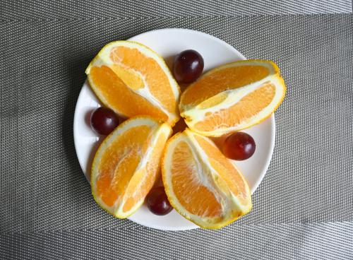 a plate of orange slices and grapes on a table at MIZPARTON HOTEL - Heshan Xinhua City Store in Jiangmen