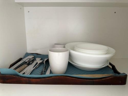 a tray with bowls and utensils on a shelf at Quiet, private studio 1 double bed and extra matress in Mount Pritchard