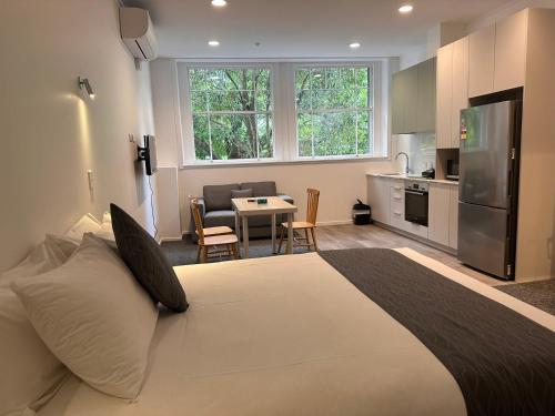 a bedroom with a large white bed and a kitchen at Gamma Hotel in Auckland