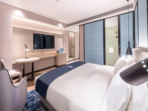 a hotel room with a large white bed and a desk at Echarm Hotel Nanning Jinhu Square Metro Station Branch in Nanning