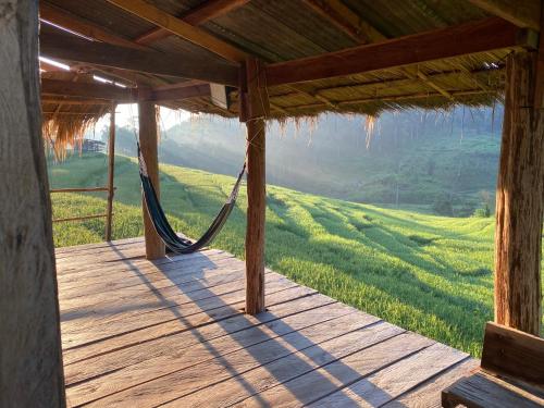 a porch with a hammock and a green field at Pang Ma - O rice terrace นาขั้นบันไดบ้านปางมะโอ in Ban Pha Mon