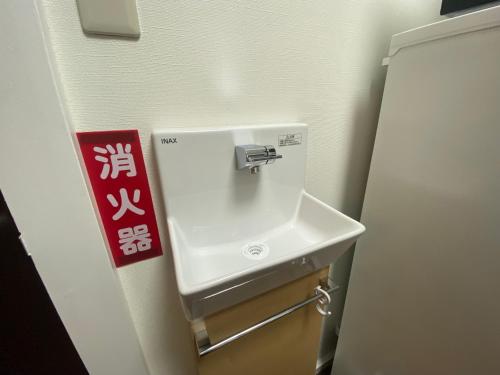 a white sink in a bathroom with a red sign at e101 長期滞在におすすめ最寄り駅阿佐ヶ谷駅2人でゆとりある宿です in Tokyo