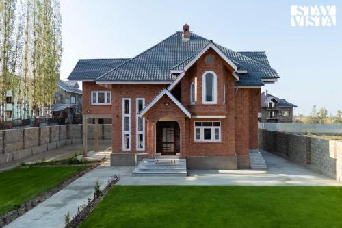 a brick house with a green lawn at StayVista at Shehjar with Mountain View, Garden in Tangmarg