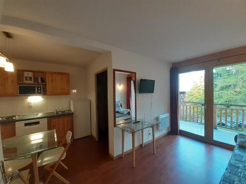 Il comprend un salon avec une table et une cuisine avec un balcon. dans l'établissement Appartement 3 pièces proche télécabine, 2 chambres, skis aux pieds, parking offert - FR-1-561-135, à Modane