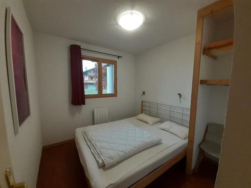 une petite chambre avec un lit et une fenêtre dans l'établissement Appartement 3 pièces proche télécabine, 2 chambres, skis aux pieds, parking offert - FR-1-561-135, à Modane