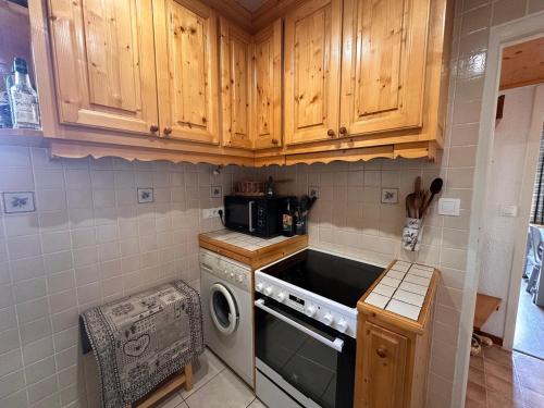 - une cuisine avec des placards en bois et un lave-linge dans l'établissement Spacieux 3 pièces, proche centre, animaux admis - FR-1-464-241, à Pralognan-la-Vanoise