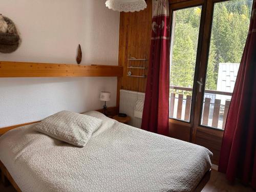 une chambre avec un lit et une grande fenêtre dans l'établissement Spacieux 3 pièces, proche centre, animaux admis - FR-1-464-241, à Pralognan-la-Vanoise