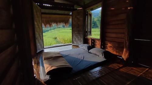 a bed in a room with a large window at Pang Ma - O rice terrace นาขั้นบันไดบ้านปางมะโอ in Ban Pha Mon
