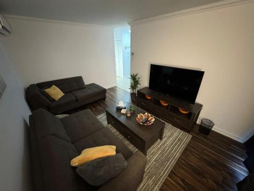 a living room with a couch and a flat screen tv at Ste-Rose 2 bedroom apt in Laval