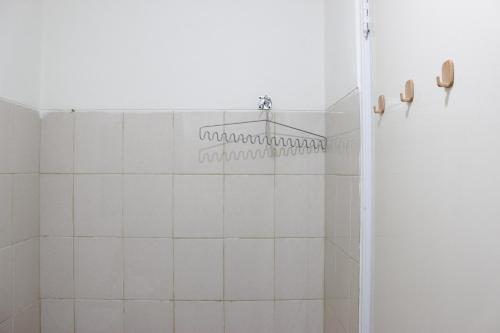 a bathroom with a shower with white tiles at Compact Studio Tamansari Panoramic Apartment By Travelio in Bandung