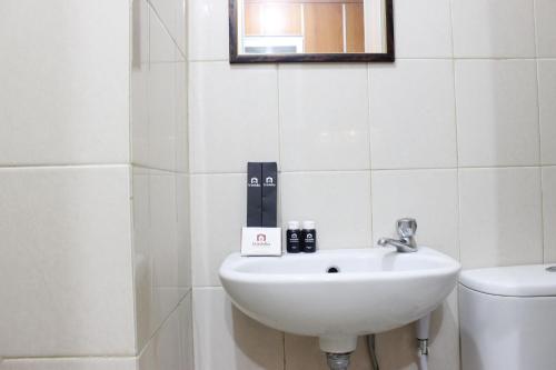 a bathroom with a sink and a toilet at Compact Studio Tamansari Panoramic Apartment By Travelio in Bandung