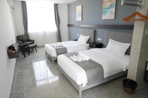a hotel room with two beds and a chair and a desk at Bohol Panglao Begonia Resort in Panglao