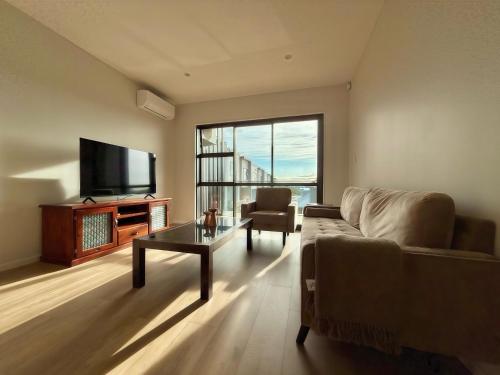 a living room with a couch and a tv and a table at Lake Quarter Apartment in Auckland