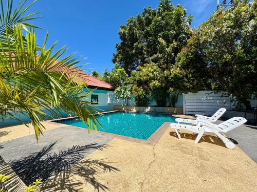 a swimming pool with two white chairs next to a house at 2 bedroom bungalow Nai Harn 4 Resort in Ban Suan
