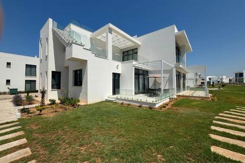 a large white house with a large yard at Stylish apartment near the sea with direct pool access and top facilities in Ayios Nikolaos