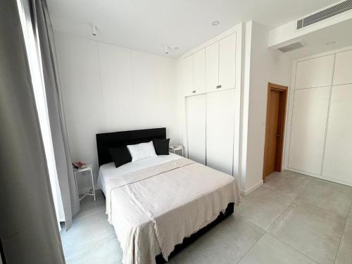 a bedroom with a bed in a white room at Stylish apartment near the sea with direct pool access and top facilities in Ayios Nikolaos