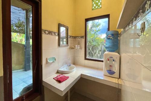 a bathroom with a toilet and a sink and a window at Mongan Homestay Beside The Belulang Hot Spring in Penebel