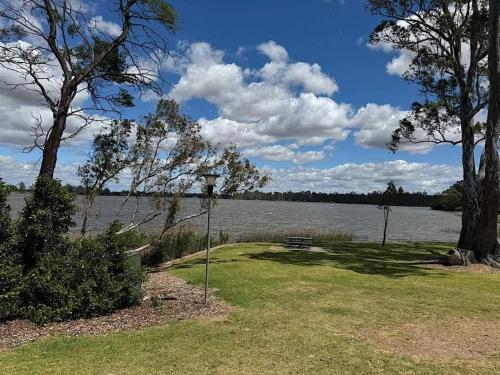 a park with a bench next to a body of water at The River Rest in Nagambie in Nagambie