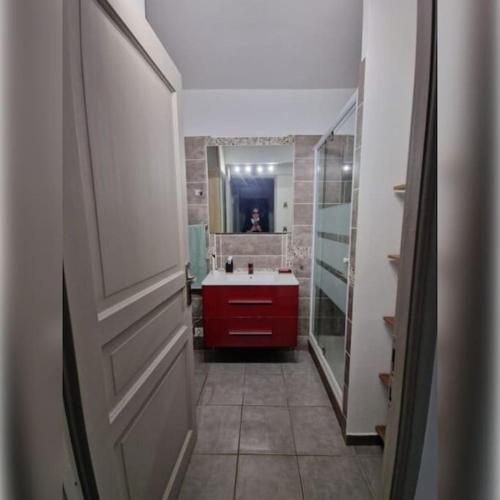 La salle de bains est pourvue d'un lavabo rouge et d'une porte rouge. dans l'établissement Rez-de-jardin à 3 min à pied de la plage des Sablettes, à La Seyne-sur-Mer