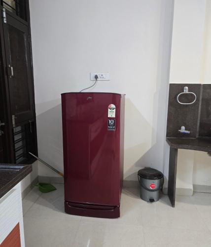 a red refrigerator in the corner of a kitchen at Satyabhama HomeStay-Pearl-Luxury two BHK Appartment in Indore