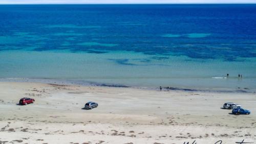 three cars parked on a beach near the ocean at Puesta de Sol Apartment by Wine Coast Holidays in Sellicks Beach