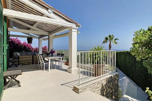 une pergola et une table sur une terrasse donnant sur l'océan dans l'établissement Villa Solberg, à Villeneuve-Loubet