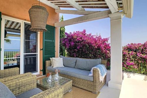 une terrasse couverte avec un canapé et des chaises. dans l'établissement Villa Solberg, à Villeneuve-Loubet