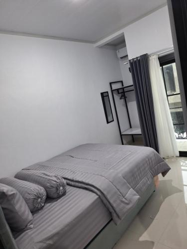 a bed in a white room with a window at White House Royal Villa B1 in Balong
