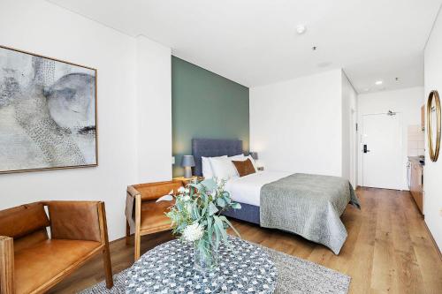 a bedroom with a bed and a vase of flowers on a table at Small Moments in Perth