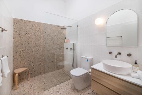 Un baño con lavabo, inodoro y ducha. en Ocean Street Oasis, en Mollymook