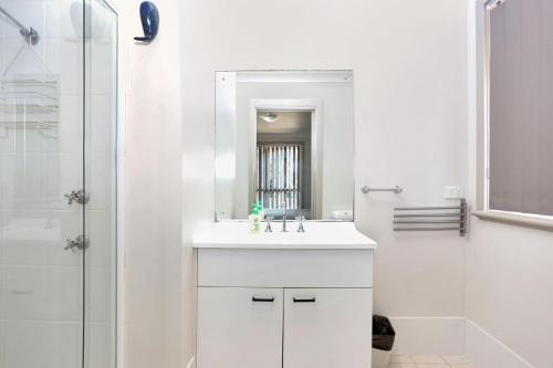 a white bathroom with a sink and a shower at Close to Jimmys Beach in Hawks Nest