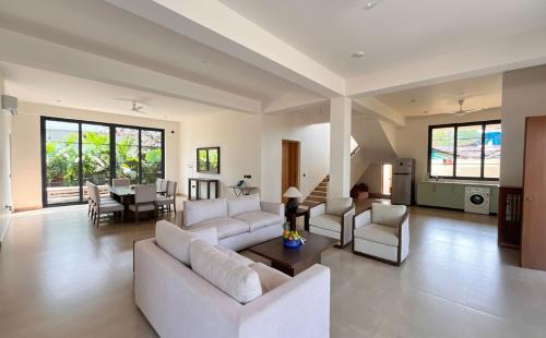 una gran sala de estar con sofás blancos y una mesa. en Beach front villa Ashwem Ocean, en Mandrem
