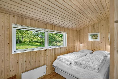 a bed in a wooden room with a window at Nice Home In Knebel With 3 Bedrooms in Knebel