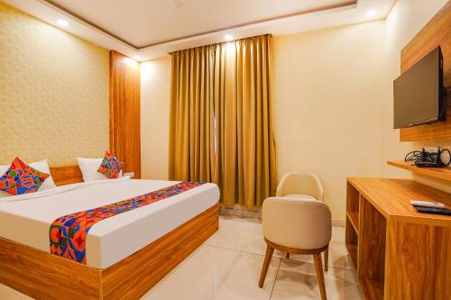 a bedroom with a bed and a television and a chair at FabHotel Prime The Waves in Bengaluru
