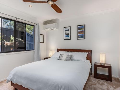 Un dormitorio blanco con una cama y una ventana. en Beachside Escape on Cottonwood, en Casuarina