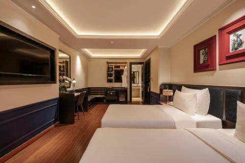 a hotel room with two beds and a desk at Champton Hanoi Hotel in Hanoi