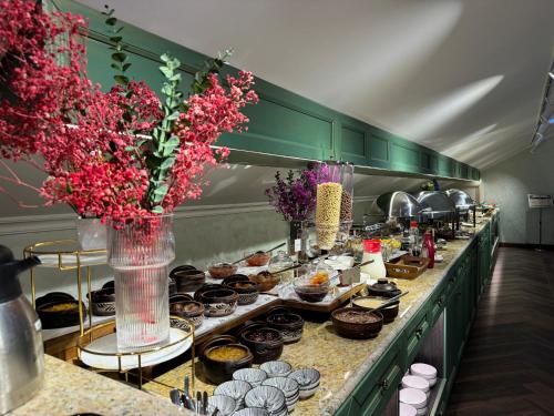 a buffet line with desserts and vases with flowers at Midway Hotel Baku in Baku