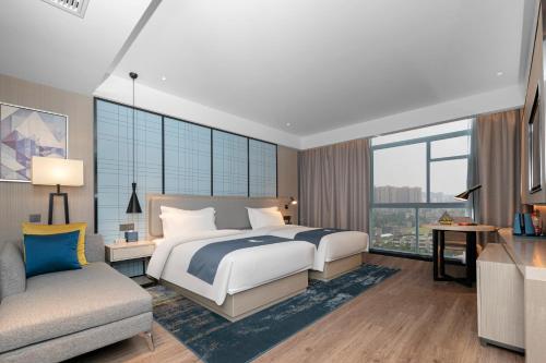 una camera da letto con un letto, un divano e una finestra di Eharm Hotel Jingzhou Olympic Sports Center a Jingzhou