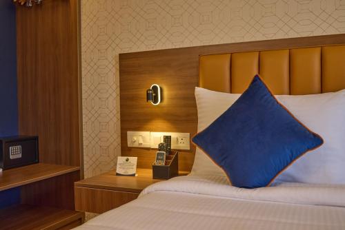 a hotel room with a bed with a blue pillow at Grand Continent Brookefield - A Sarovar Portico Affiliate Hotel in Bengaluru