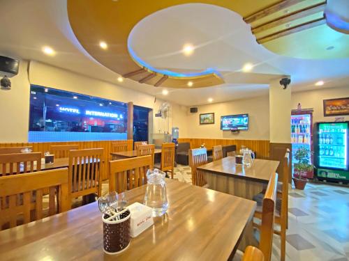 a restaurant with wooden tables and chairs and a large screen at Hotel Airport Holiday in Kathmandu