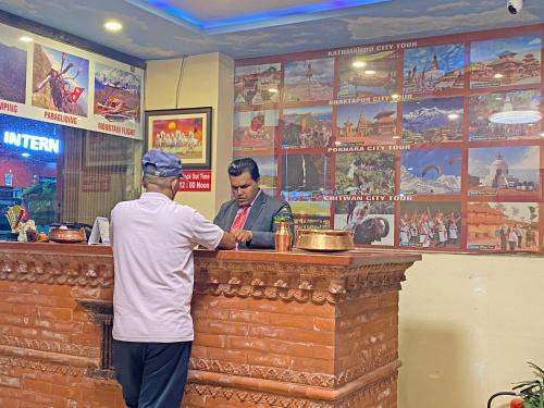 a man standing at a bar talking to a man at Hotel Airport Holiday in Kathmandu