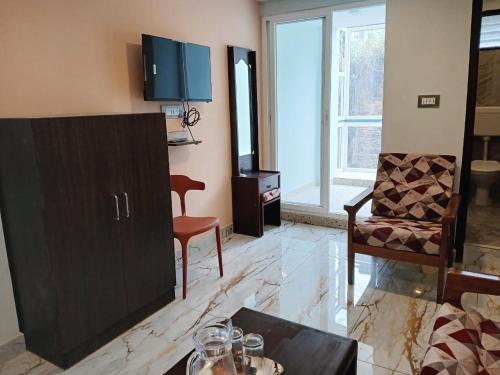 a living room with a cabinet and a chair at Ponmurugan Residency in Kodaikānāl