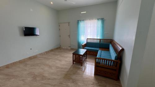 a living room with a blue couch and a television at The Karlyle Homestay in Vaduvanchal