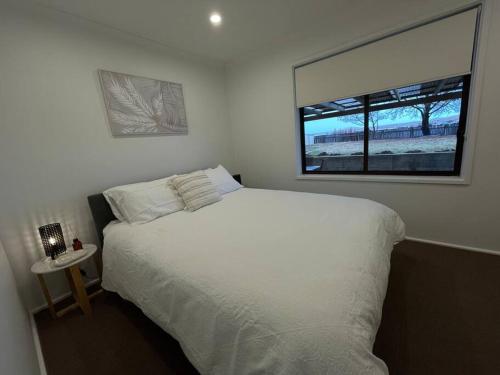 a bedroom with a white bed and a window at 3 Bedroom House in Cooma in Cooma